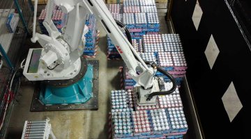 Overhead view of a Mixed-Case Palletizing Robot picking cases from conveyor and building a Mixed-SKU, also known as Rainbow pallets.