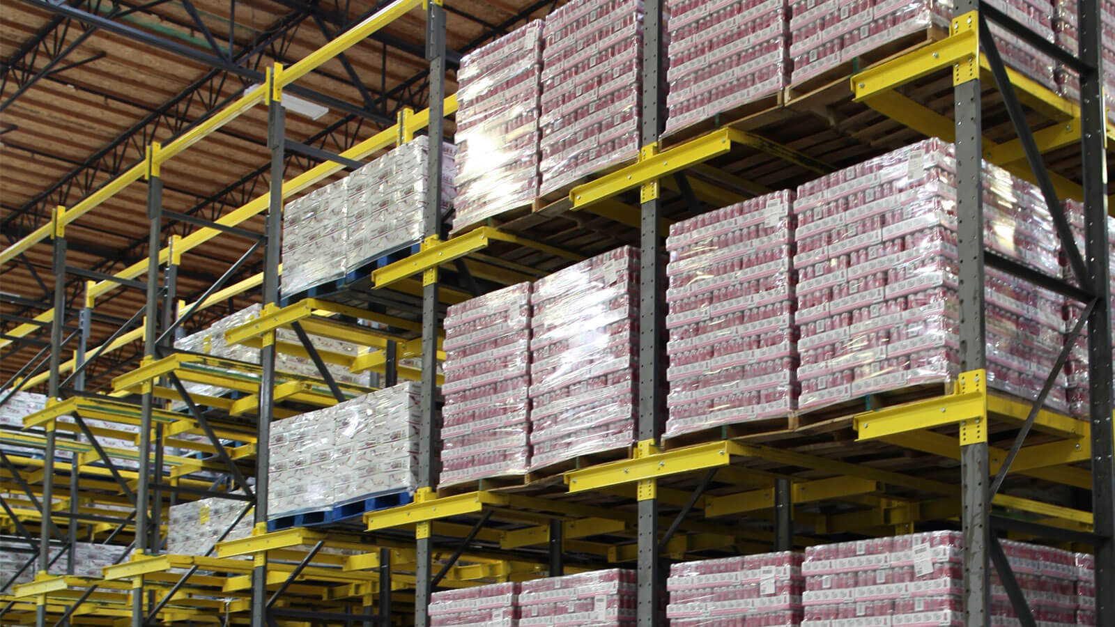 Spacious beverage co-packer and distributor warehouse showcasing multiple levels of Twinlode Dual-Wide Pallet Racking. Stacked pallets, organized in neat rows, hold boxes of beverages.
