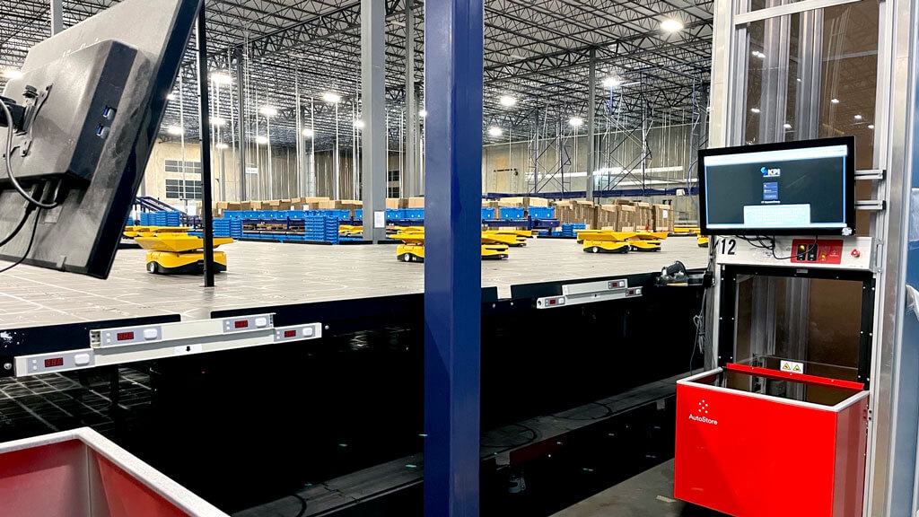 LT Apparel Group AutoStore ASRS Pick-to-Light Station with Robots in background.